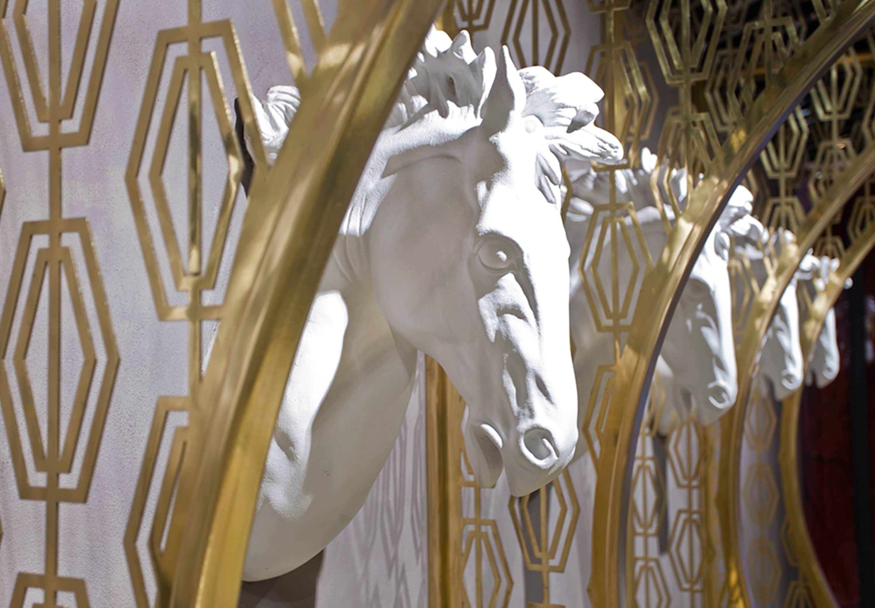 A white horse head sculpture with a geometric patterned background.