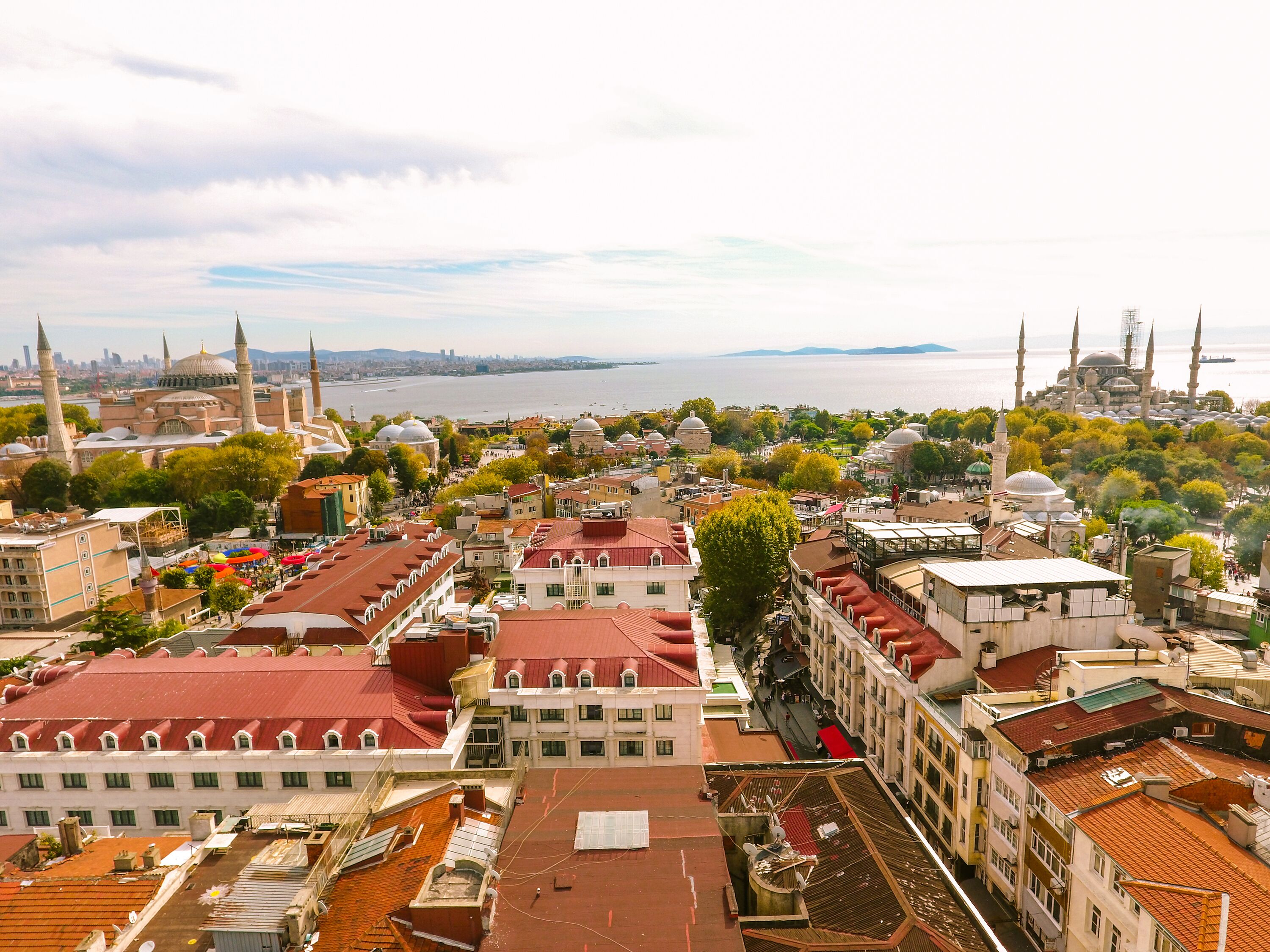 A cityscape with a prominent mosque with multiple domes and minarets, surrounded by buildings with red-tiled roofs.