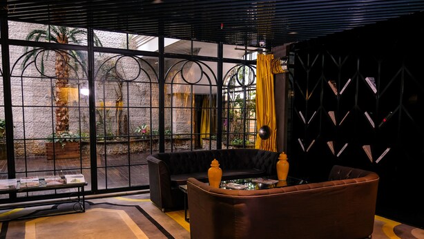 A modern interior with a large window, a black sofa, and a brown armchair. - Sura Design Hotel and Suites - Boutique Class (Istanbul)