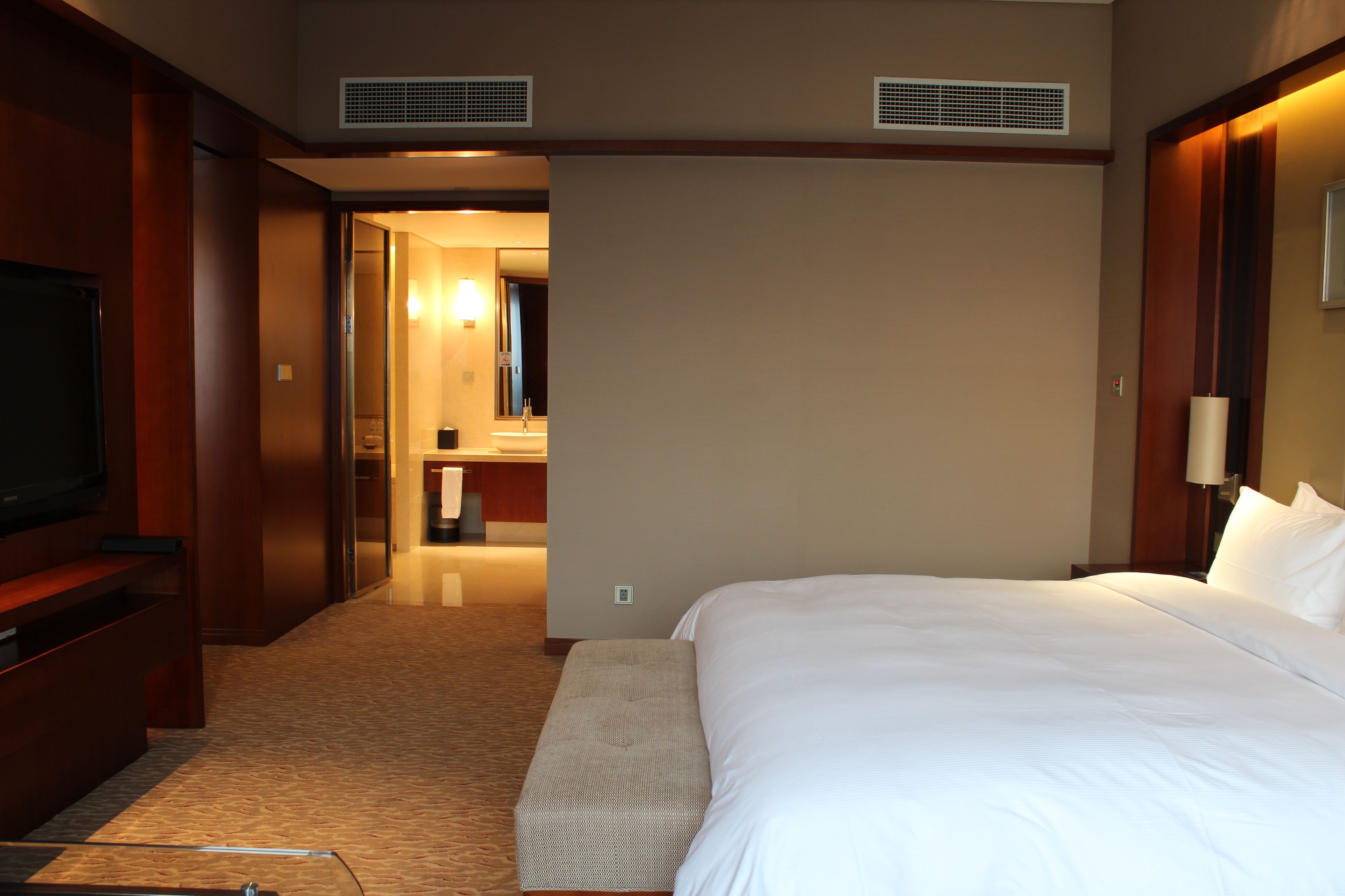 Une chambre d’hôtel avec un grand lit, une télévision et une salle de bain visible à travers une porte ouverte.