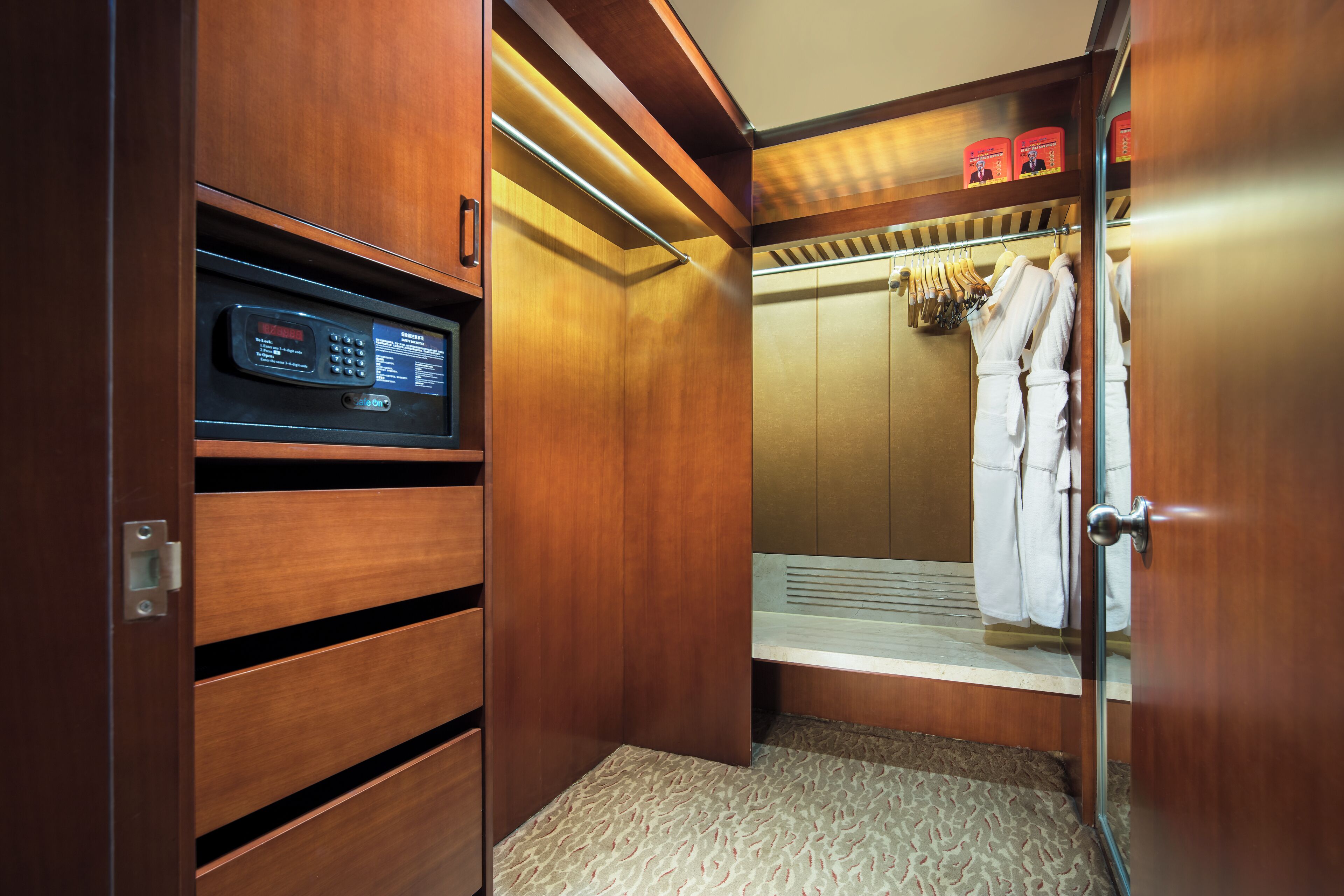 Une chambre d’hôtel dotée d’une armoire en bois, d’un coffre-fort intégré et d’un porte-peignoir avec des serviettes.