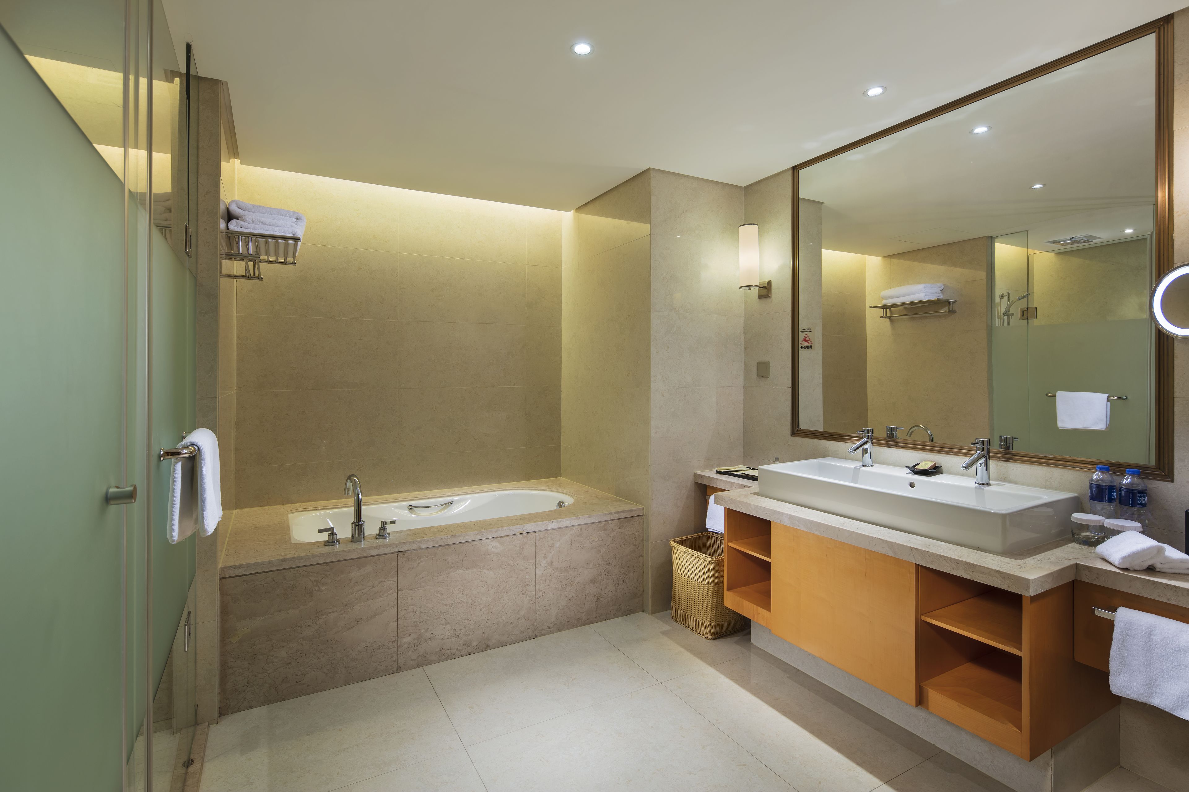 A modern bathroom with a bathtub, two sinks, and a large mirror.