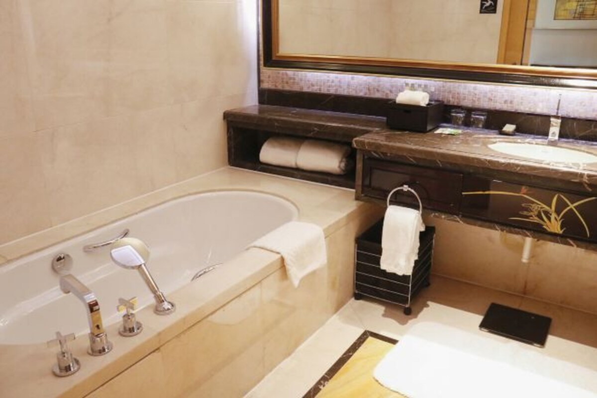 Un baño moderno con bañera, lavamanos y un espejo grande.