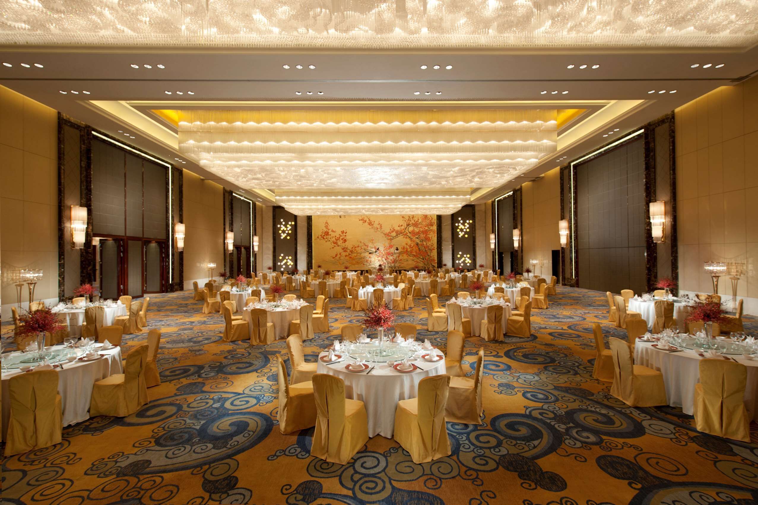 Une grande salle de banquet avec des tables rondes, des chaises et un plafond décoratif.