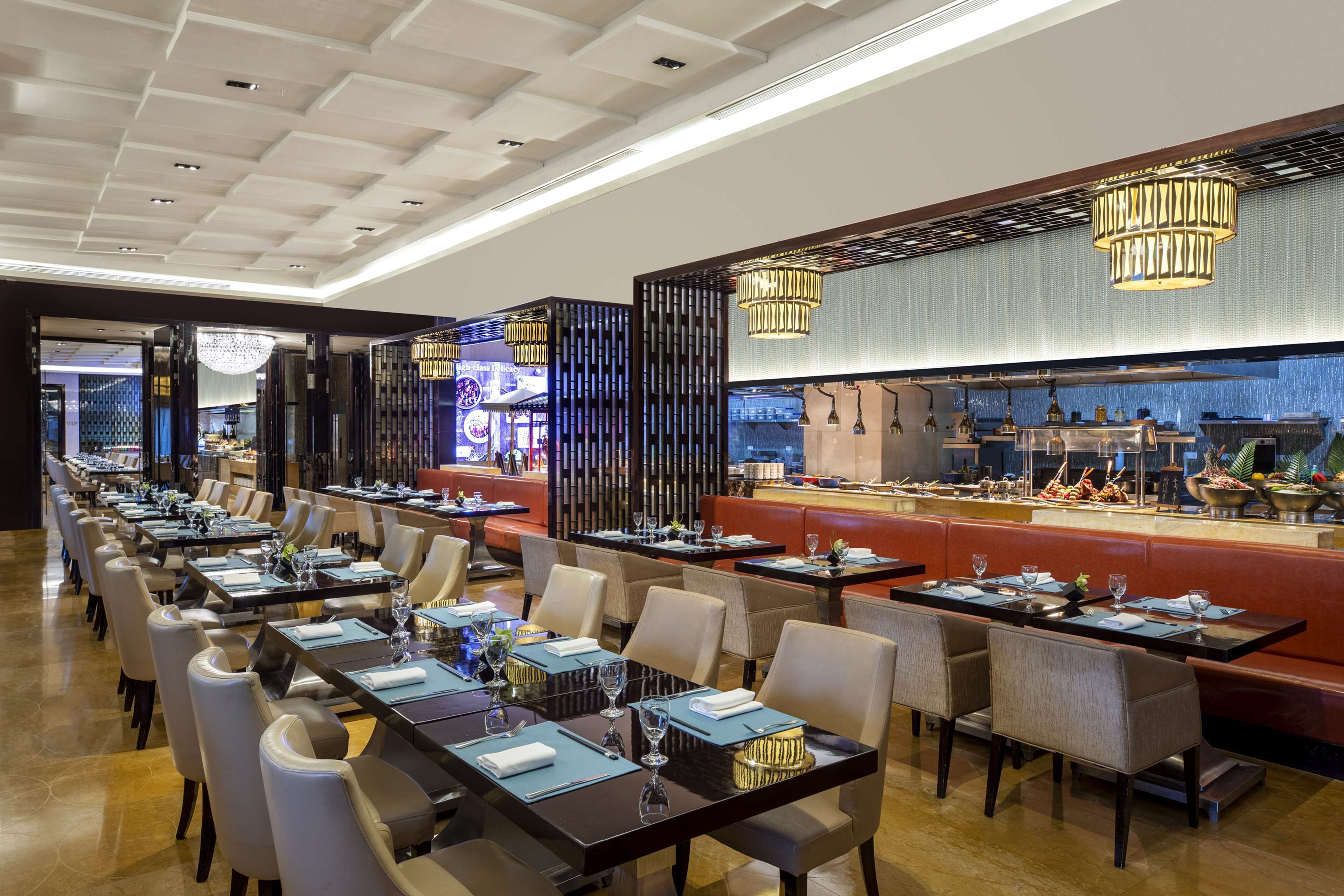 A long dining area with tables set for guests, a bar area with a counter, and a modern ceiling design.