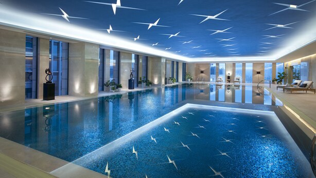 A large indoor swimming pool with a modern design, including a ceiling with star-like patterns and a well-lit, spacious area with lounge chairs. - Hilton Nanjing (Nanjing)