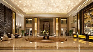 A spacious lobby with a polished marble floor, a central round table with floral arrangements, and a decorative ceiling with a cloud-like pattern. - Hilton Nanjing (Nanjing)