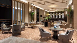 A spacious lobby with a bar area, comfortable seating, and a large bookshelf. - Hilton Nanjing (Nanjing)