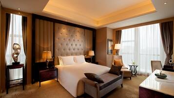 A spacious hotel room with a large bed, a sofa, a desk, and a chair.