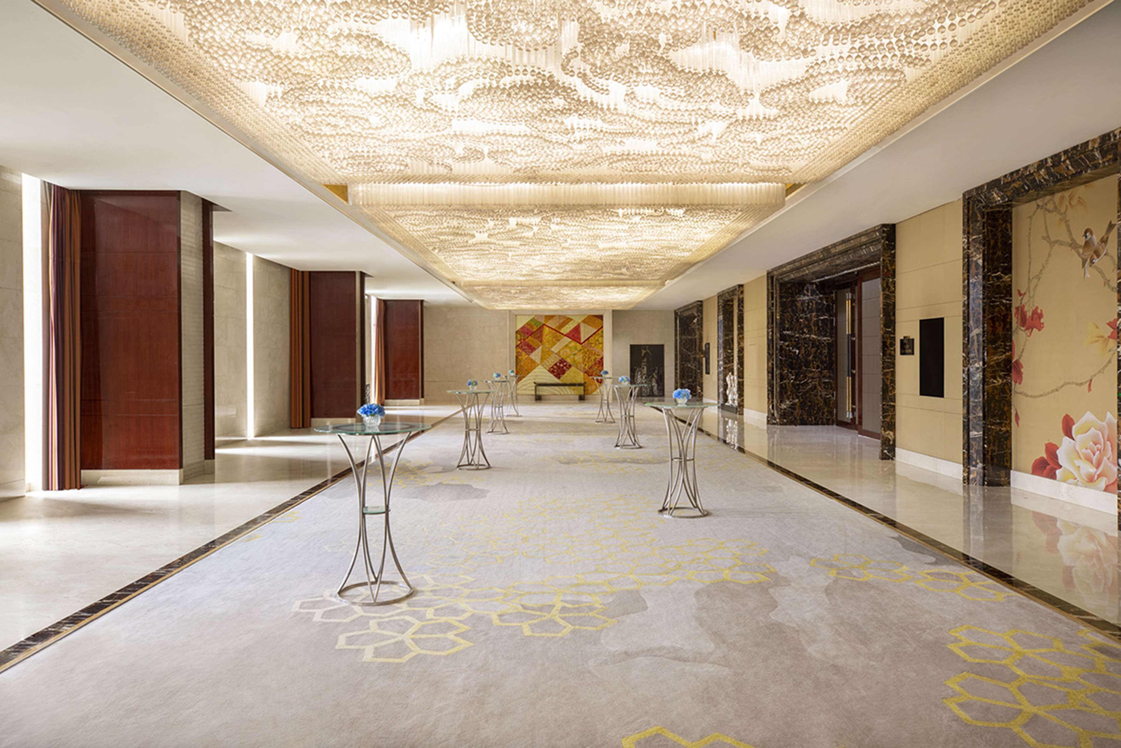 A spacious hallway with a patterned floor, a decorative ceiling, and a mural on the wall.