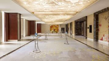 A spacious hallway with a patterned floor, a decorative ceiling, and a mural on the wall.