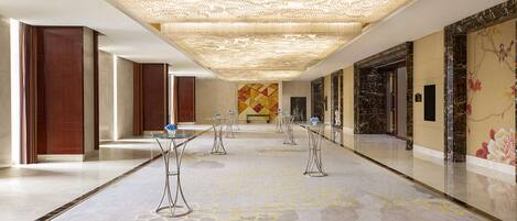 A spacious hallway with a patterned floor, a decorative ceiling, and a mural on the wall.
