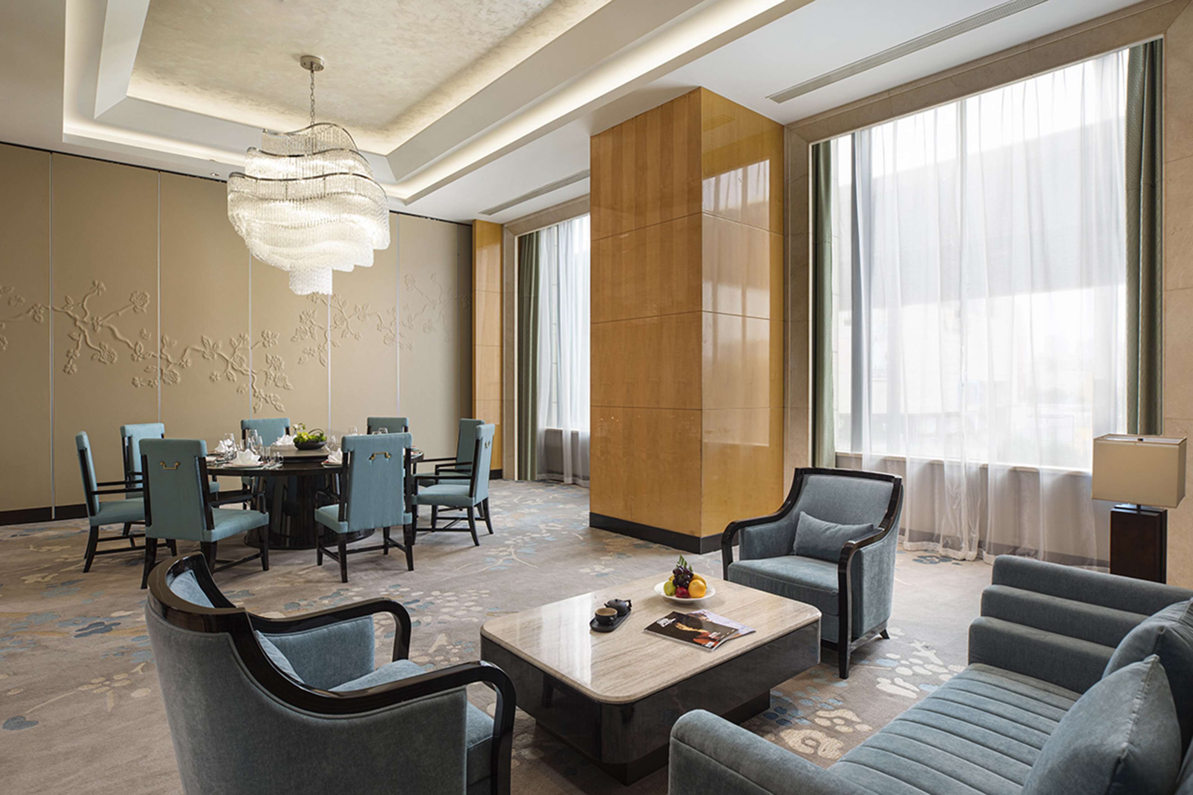 Un hall d’hôtel comprenant un espace repas, des coins salon et de grandes fenêtres.