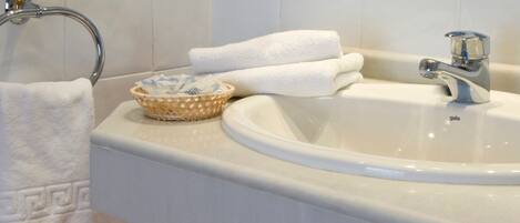 A bathroom with a white sink, a towel rack, and a decorative blue and white tile backsplash.