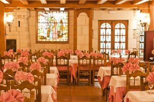 Salão de festas com mesas em fila, cada uma coberta por toalhas brancas e capas cor-de-rosa para um evento formal.