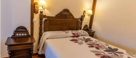A neatly made bed with a floral bedspread, a wooden headboard, and two bedside lamps.
