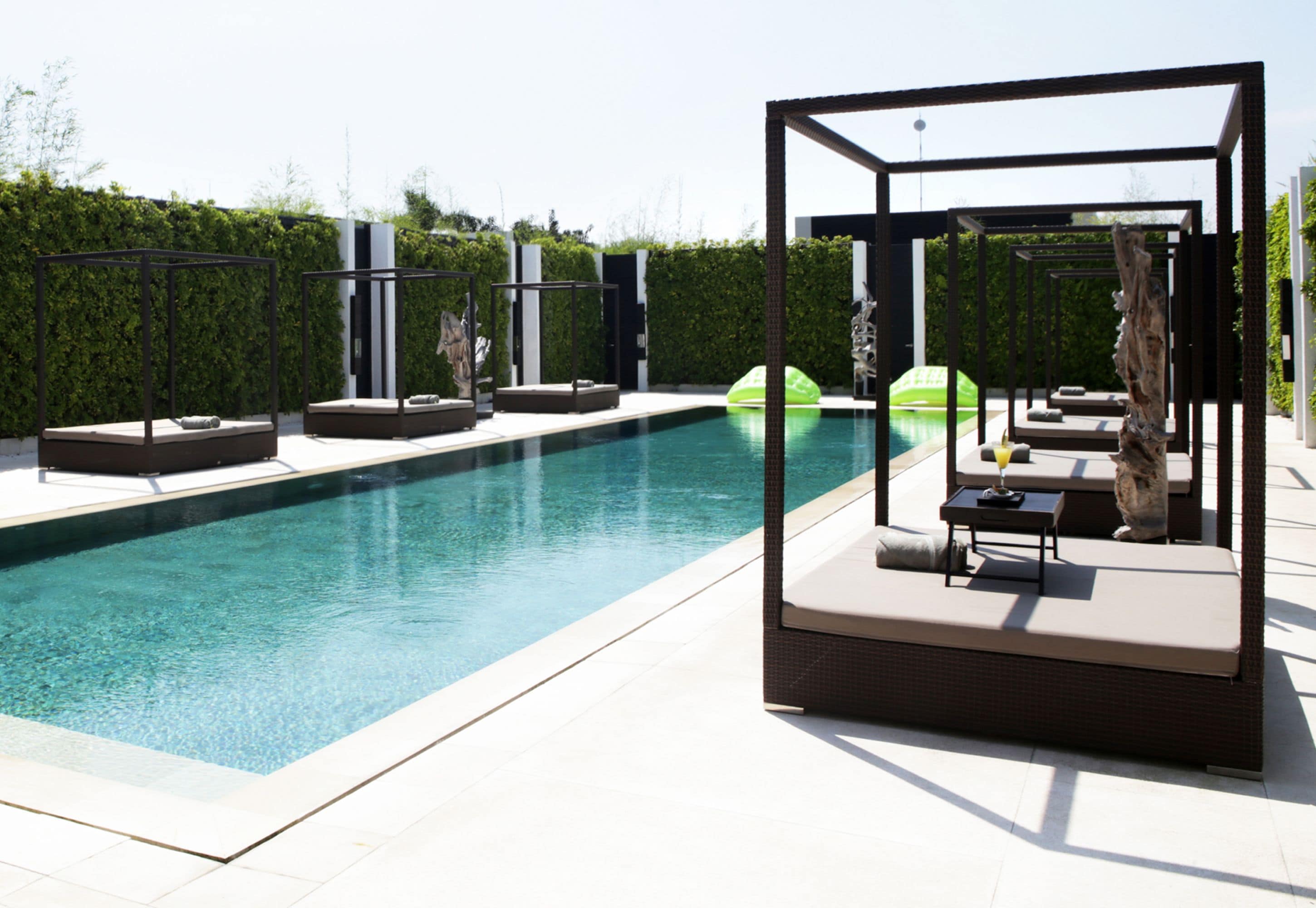 A modern outdoor pool area with lounge seating and a pergola structure.