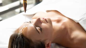 A person lying down with a treatment being applied to their head.