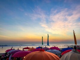 Une scène de plage avec des parasols colorés et un coucher de soleil.