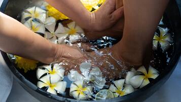 Hands submerged in water with flowers and slices of lime.