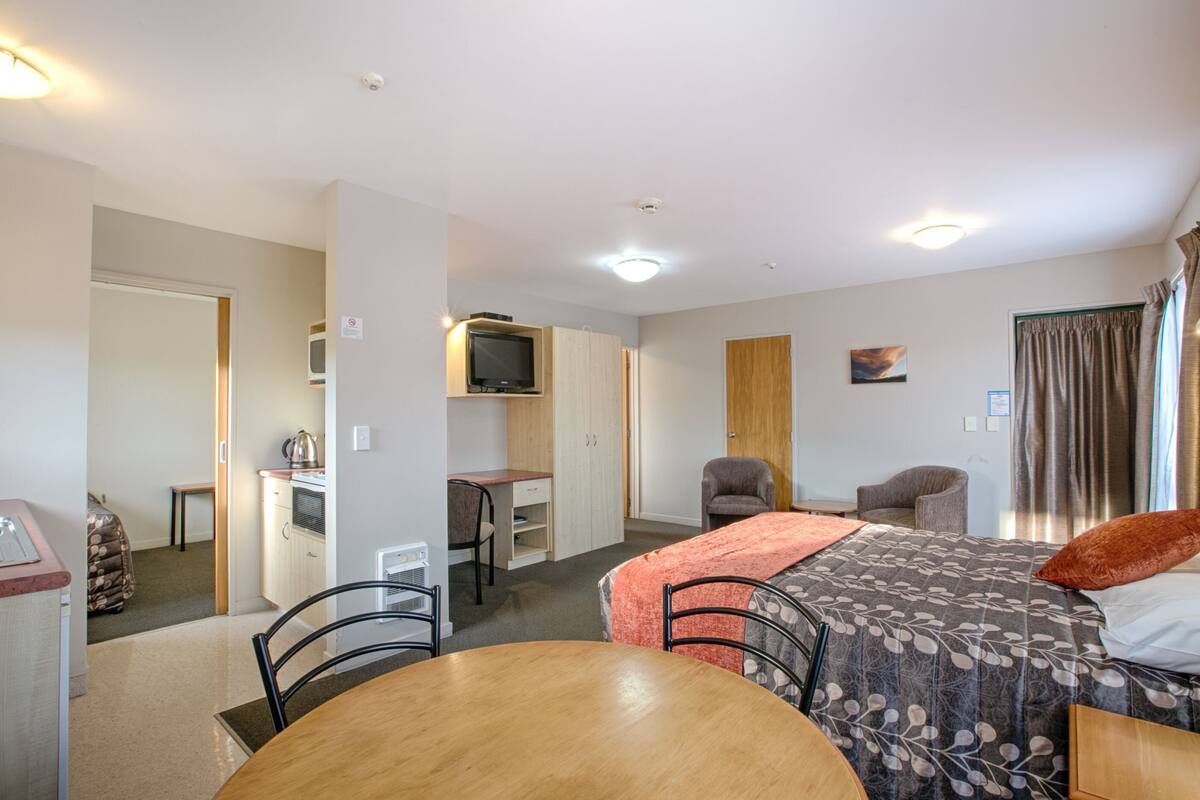 Ein Hotelzimmer mit Bett, Schreibtisch, Stuhl, Tisch und Fernseher.