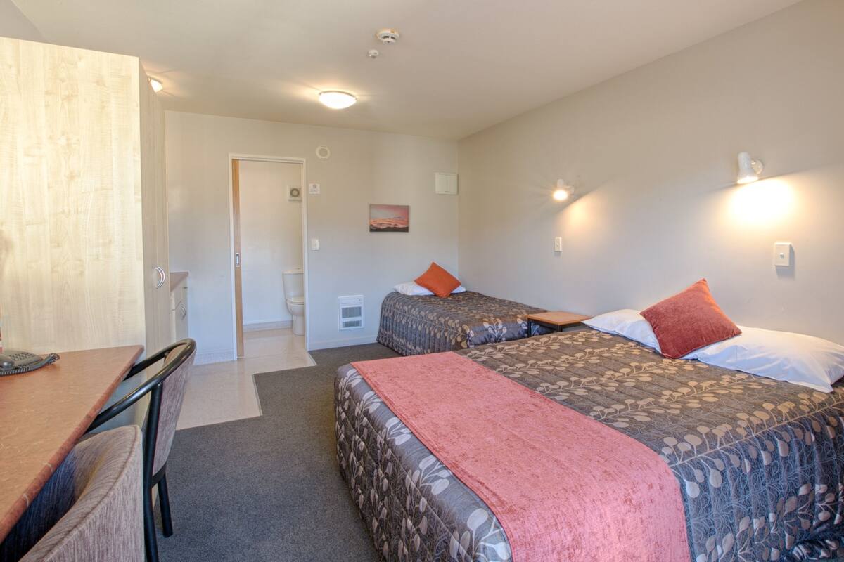 Ein Hotelzimmer mit zwei Betten, einem Schreibtisch und einem Stuhl.