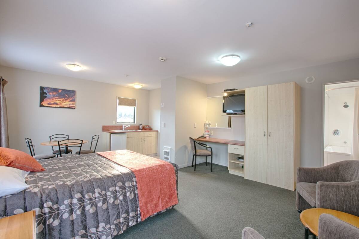 Ein Schlafzimmer mit Bett, Schreibtisch, Stuhl, Kleiderschrank und Bad.
