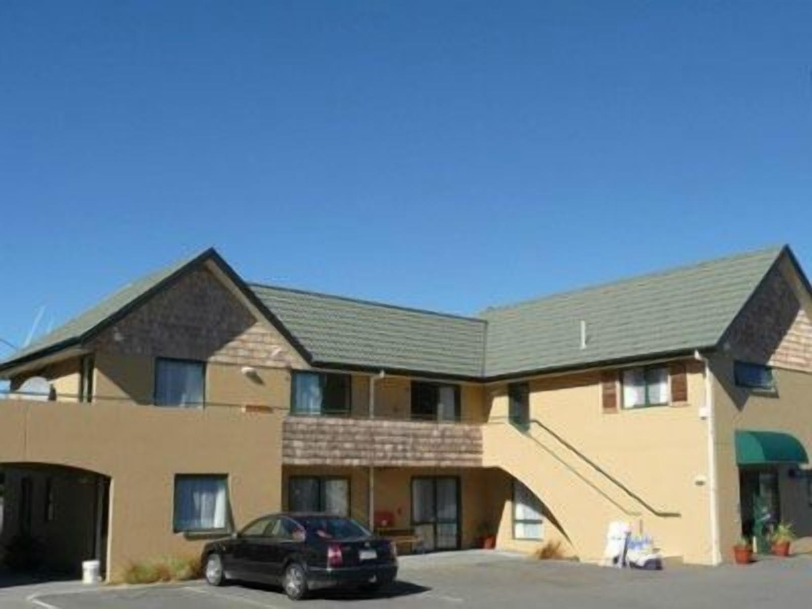 A two-story motel with a parking lot, a covered entrance, and a staircase leading to the upper level.