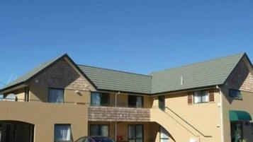 A two-story motel with a parking lot, a covered entrance, and a staircase leading to the upper level.