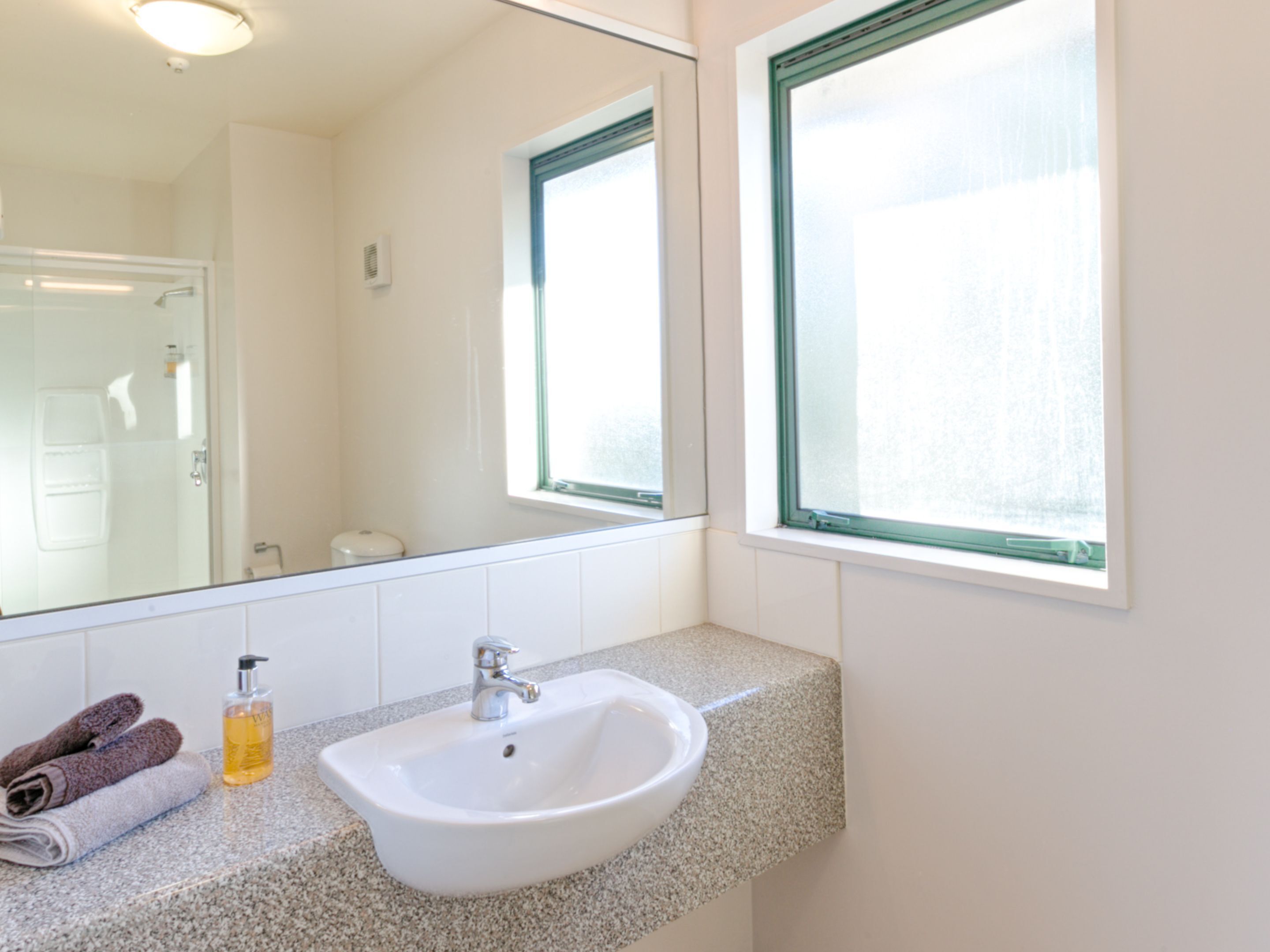 A bathroom with a white sink, a mirror, and a window.