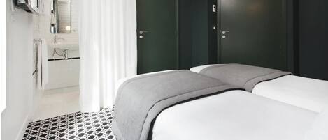 Una habitación de hotel con una cama, un baño con un lavabo y una puerta.
