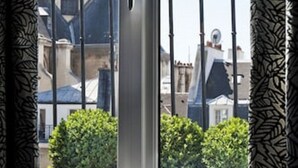 A window with a view of a building with a dome and a balcony. - Hôtel Emile Le Marais (Paris)