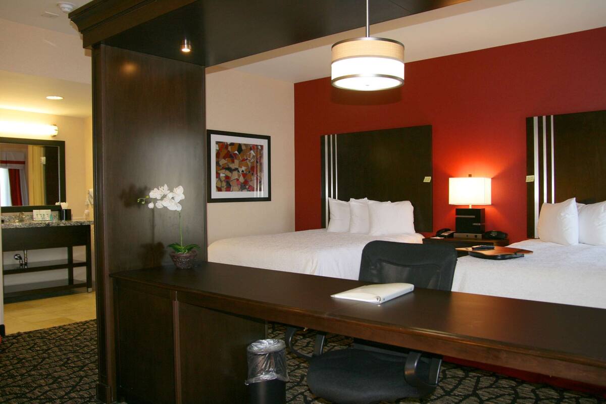 Een hotelkamer met een bed, bureau, stoel, lamp en een potplant.