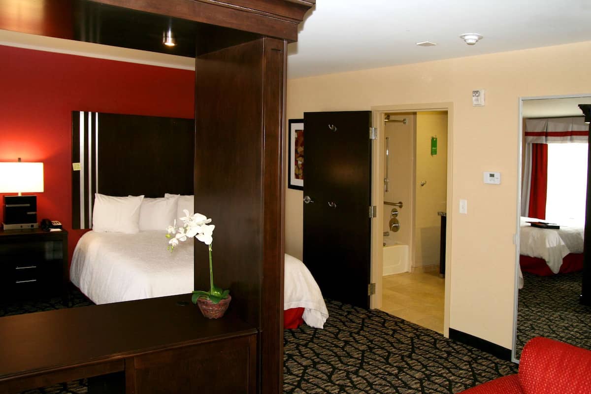 Een hotelkamer met een bed, een bureau, een spiegel en een rode stoel.