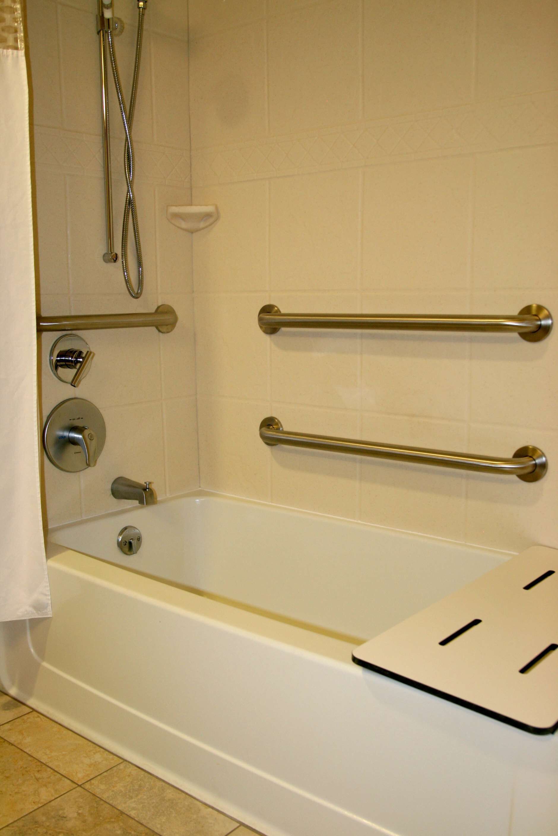 A bathtub with a showerhead, grab bars, and a control panel.