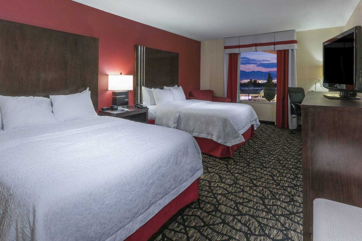 Une chambre d’hôtel avec deux lits, un bureau, une télévision et une fenêtre donnant sur la ville.