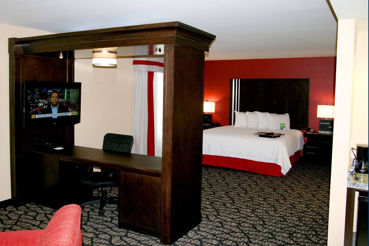 Een hotelkamer met een bed, een bureau, een televisie en een stoel.