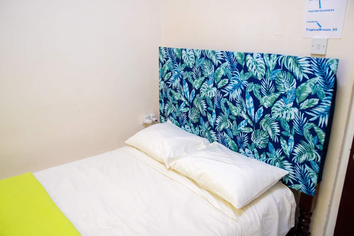 Una cama con ropa de cama blanca y un cabecero estampado con hojas azules.