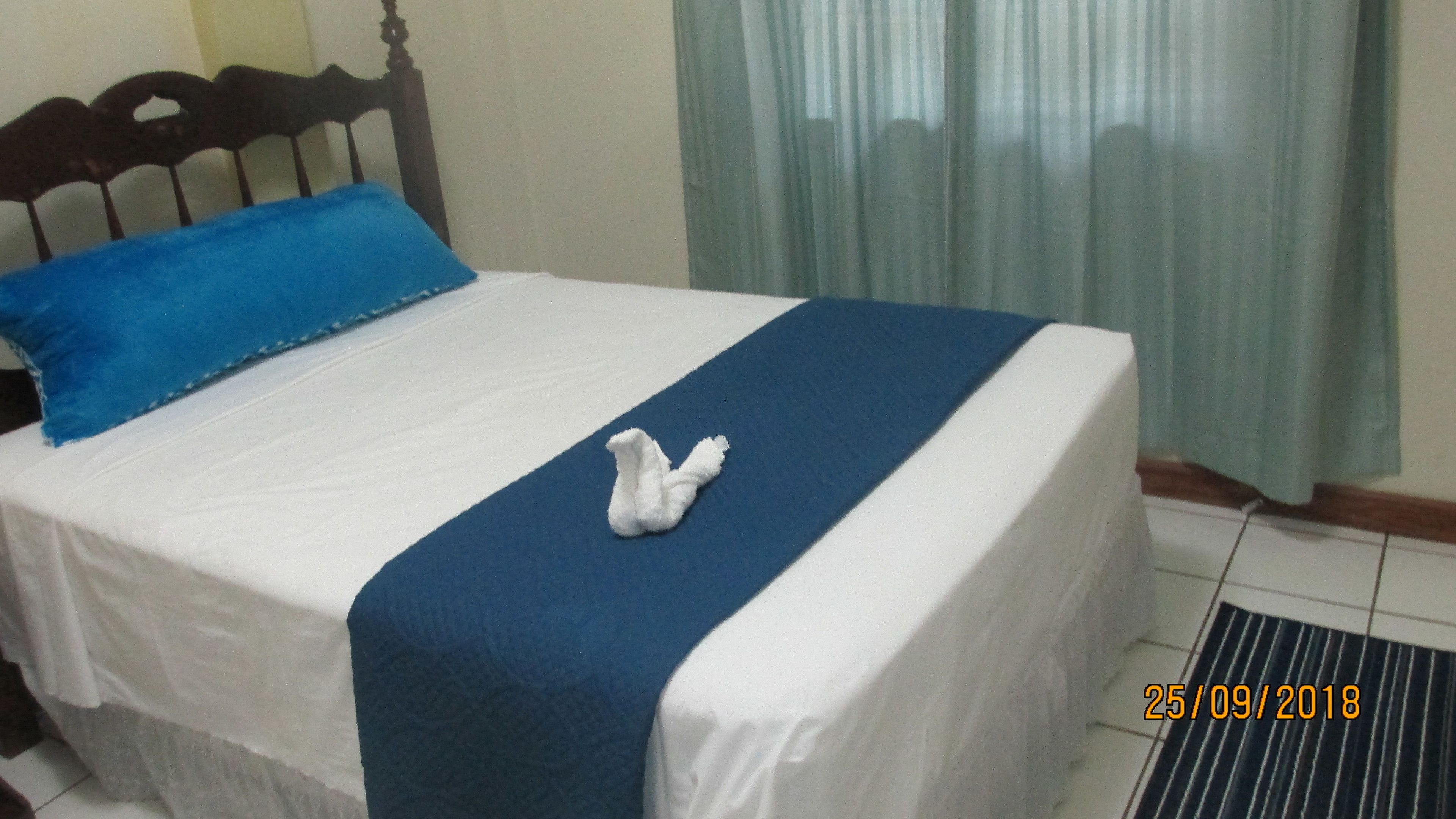 Un letto con materasso bianco, biancheria azzurra e un asciugamano bianco sopra il letto.