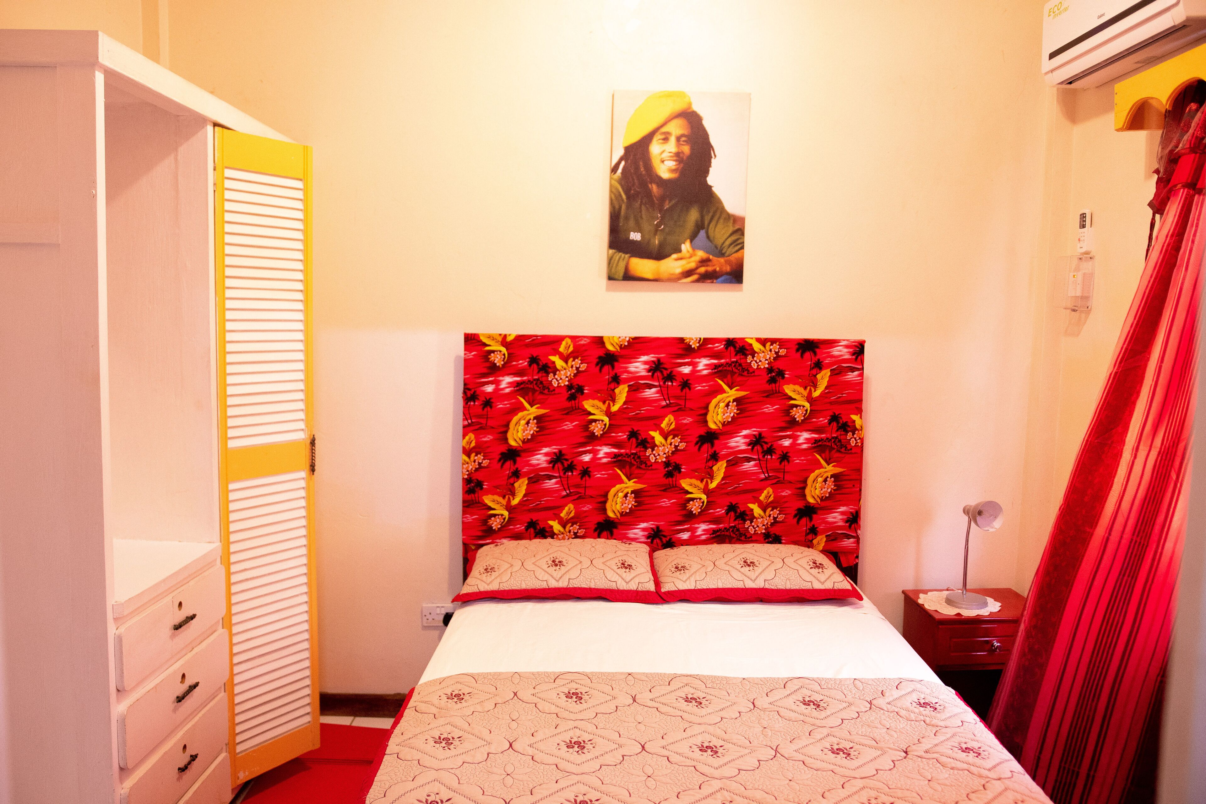 A bedroom with a bed, a wardrobe, a nightstand, and a wall-mounted picture.