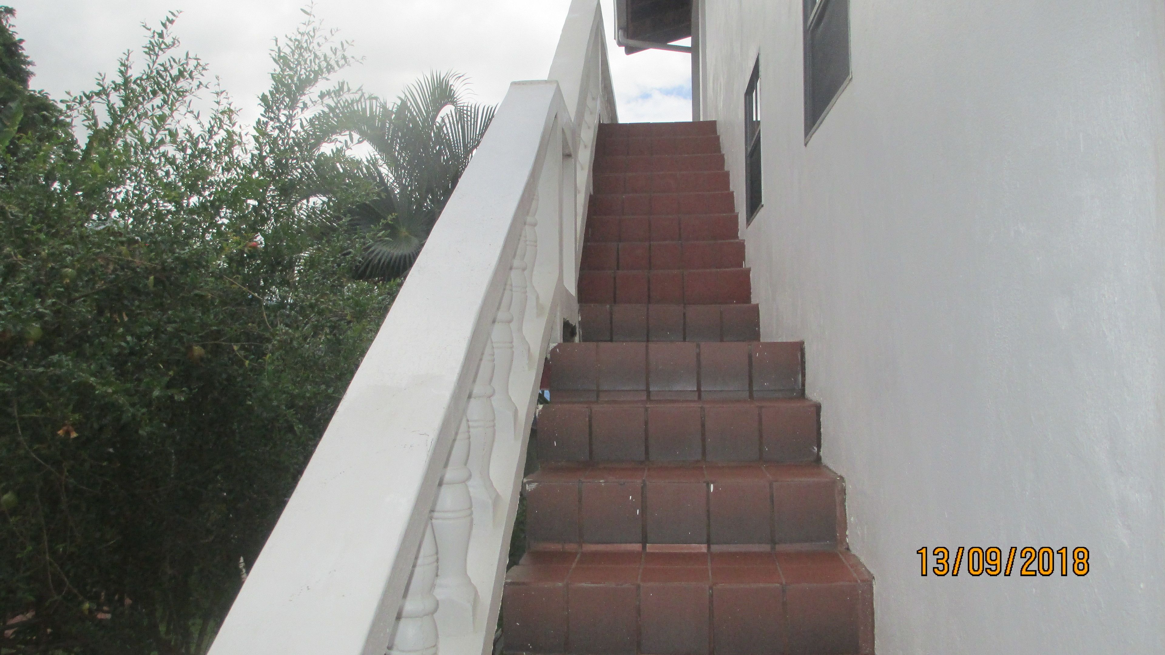 A staircase with red tiles leading up to a white building.