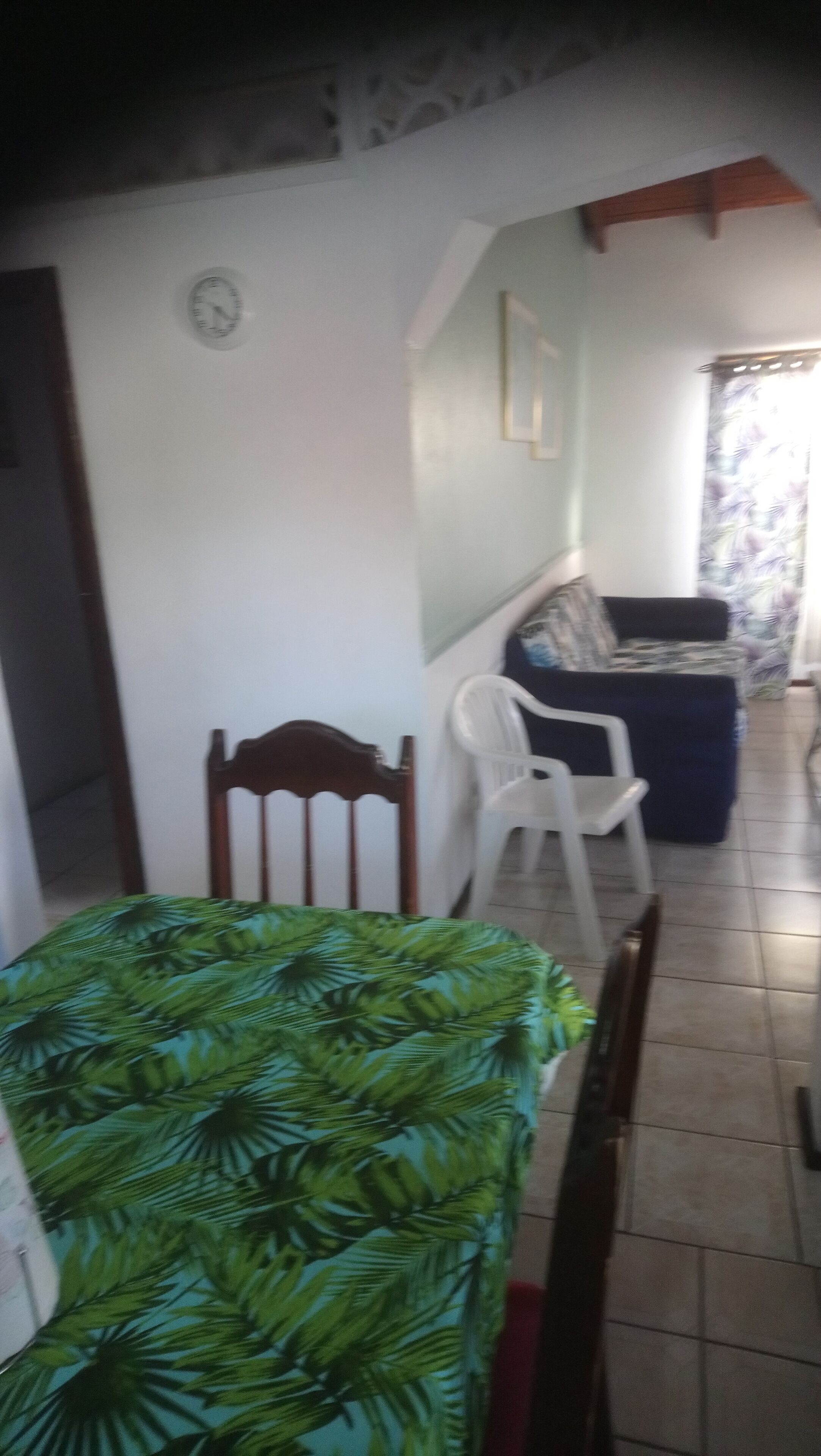 A room with a bed, a wooden chair, a sofa, and a dining table.