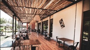 An outdoor cafe with wooden flooring, tables, and chairs. - Fuente Mayor Hotel And Resort (Tunuyan)