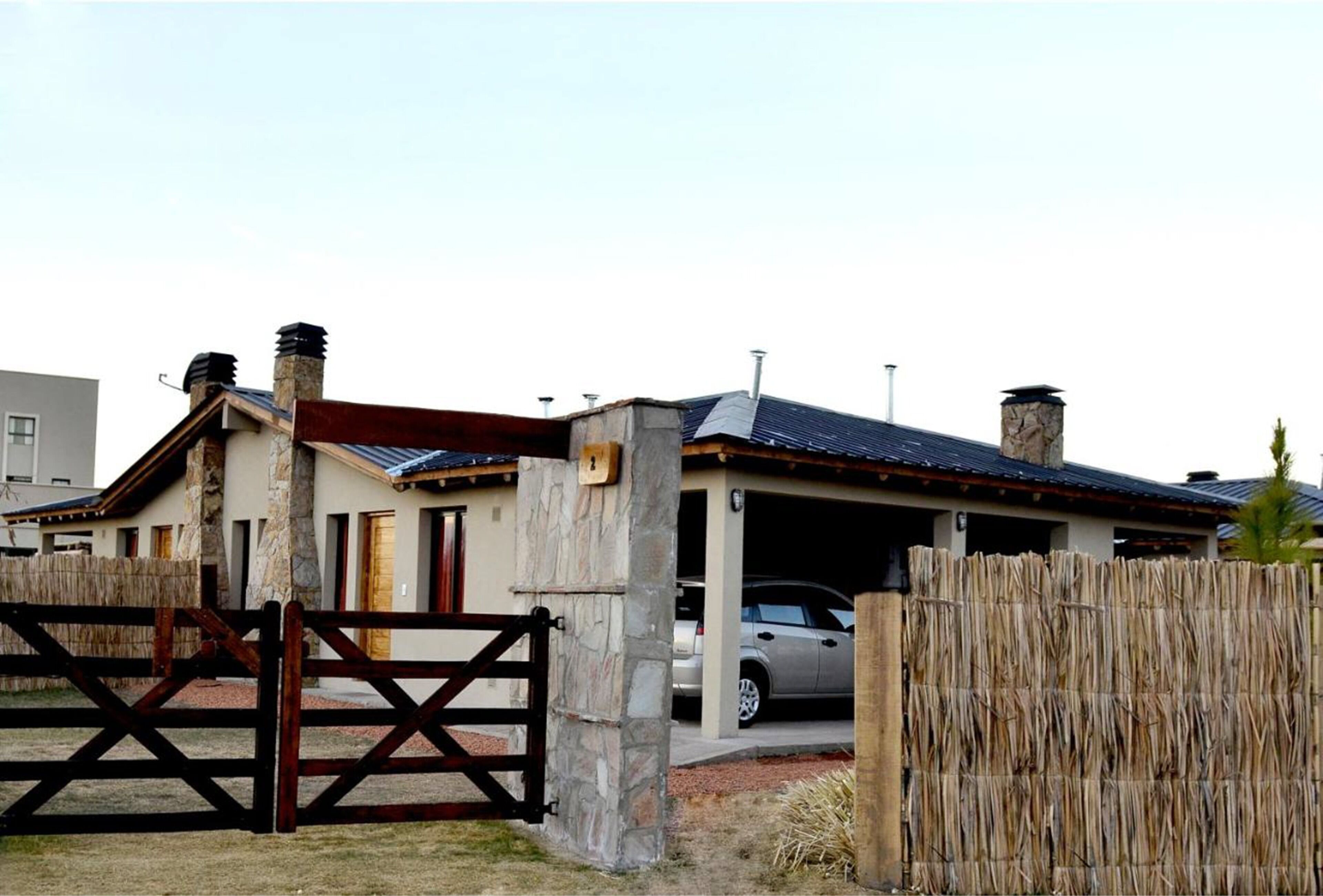 A residential building with a garage, a wooden gate, and a vehicle parked inside.