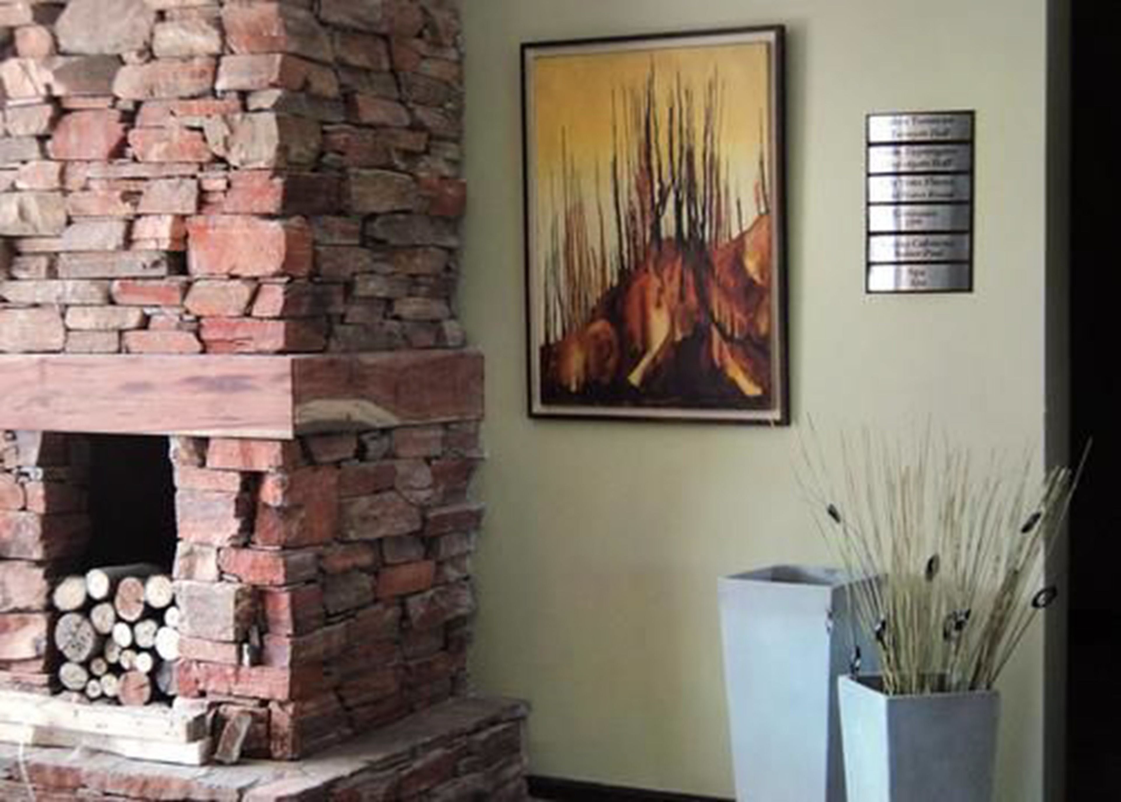 A stone fireplace with logs, a framed abstract painting, and a sign with text on the wall.