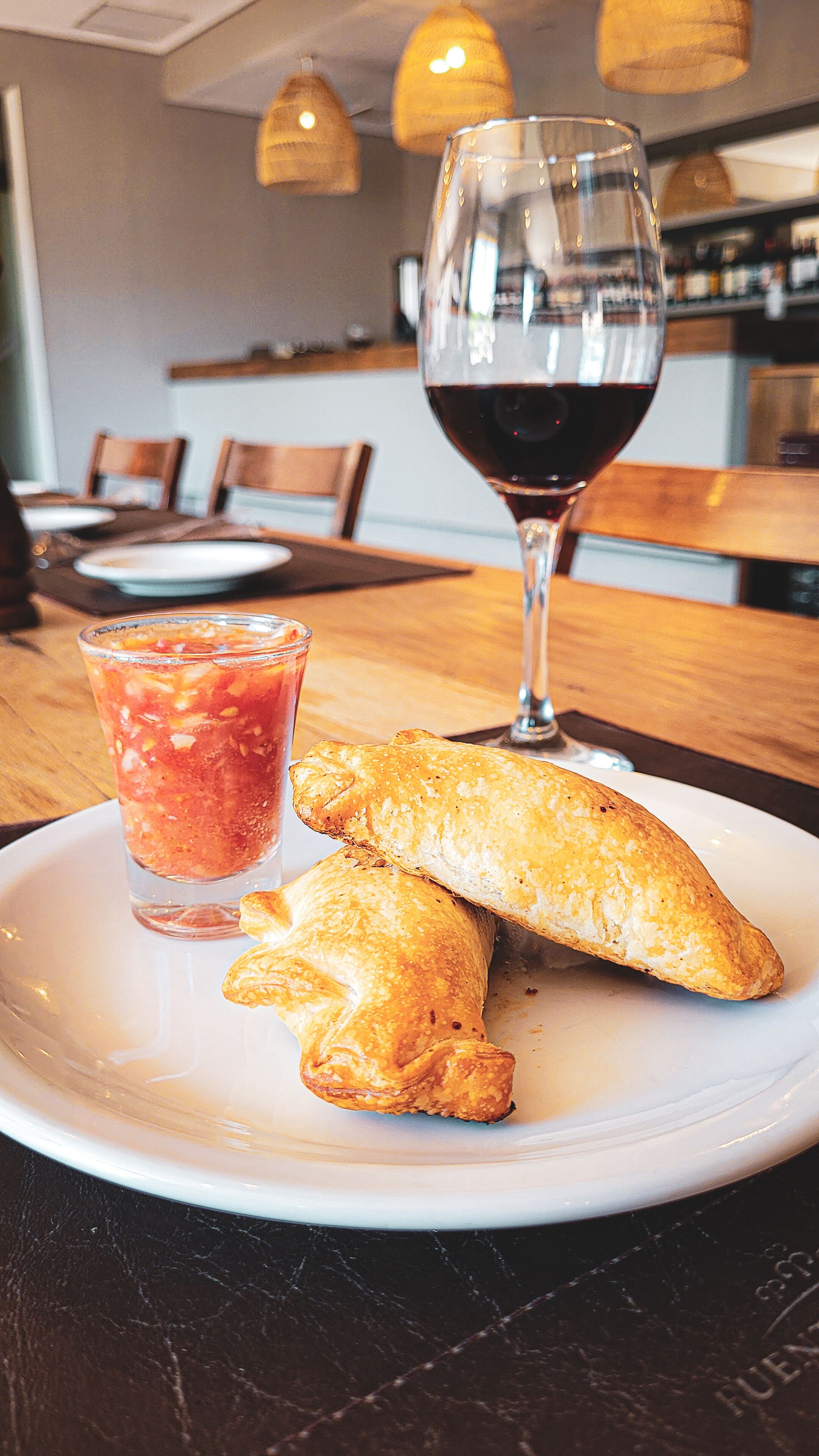 A plate with pastries and a glass of red wine on a table in a restaurant.