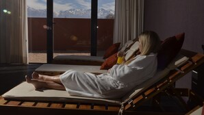 A person relaxing on a sun lounger with a mountain view through large windows. - Fuente Mayor Hotel And Resort (Tunuyan)