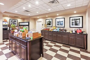 Eine Hotelküche mit kariertem Boden, einer Buffettheke und gerahmten Bildern an der Wand.