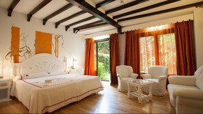Un dormitorio con cama, dos sillas, una mesita y una ventana con cortinas.