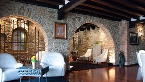 A stone-walled room with white leather sofas, a glass coffee table, and a fireplace. - Hotel Doña Teresa (La Alberca)